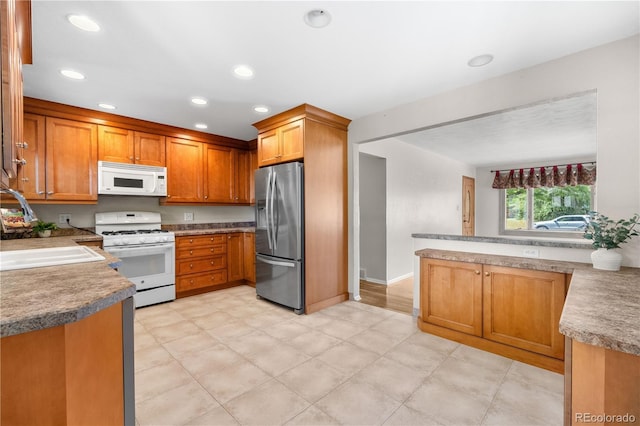 7742 W Florida Dr, Lakewood, CO 80232 - kitchen with white appliances, brown cabinets, light floors, recessed lighting, and light countertops
