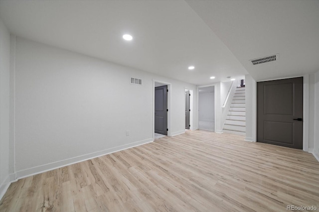 unfurnished room with stairway, light wood-style floors, baseboards, and recessed lighting