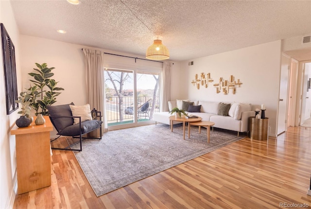 living room featuring visible vents, a textured ceiling, and wood finished floors