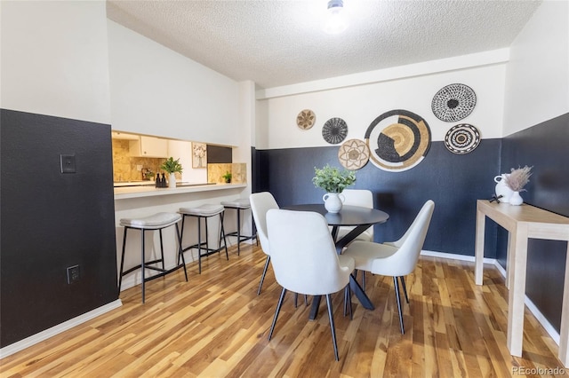 dining room with baseboards, a textured ceiling, and wood finished floors