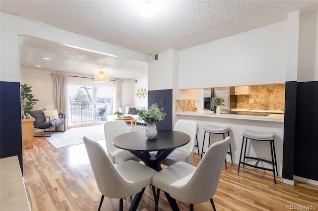 dining room featuring visible vents, a textured ceiling, and light wood-type flooring