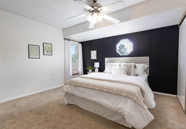 bedroom featuring a ceiling fan, light colored carpet, baseboards, and a textured ceiling