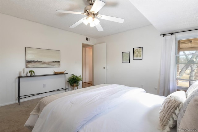 bedroom with visible vents, carpet floors, a textured ceiling, and a ceiling fan