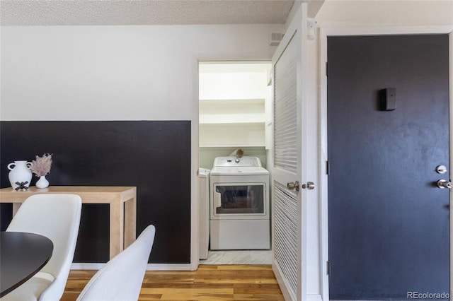 laundry area with visible vents, independent washer and dryer, a textured ceiling, wood finished floors, and laundry area