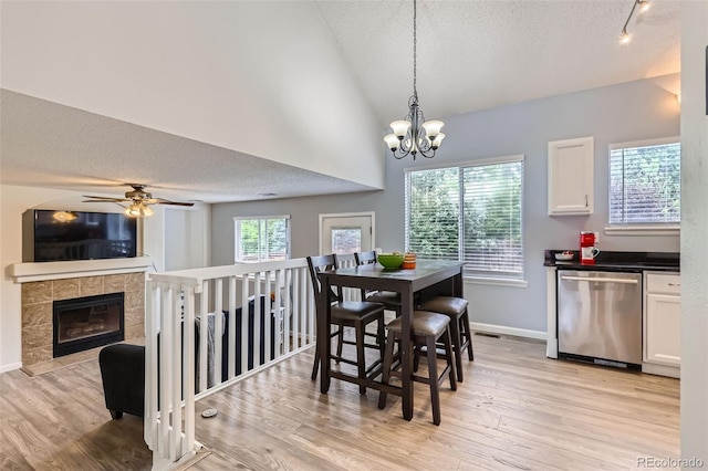 3734 Licorice Trl, Castle Rock, CO 80109 - dining room featuring a textured ceiling, light wood finished floors, a ceiling fan, a tile fireplace, and a chandelier