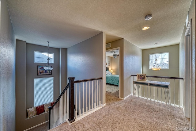 hall featuring light colored carpet and a textured ceiling