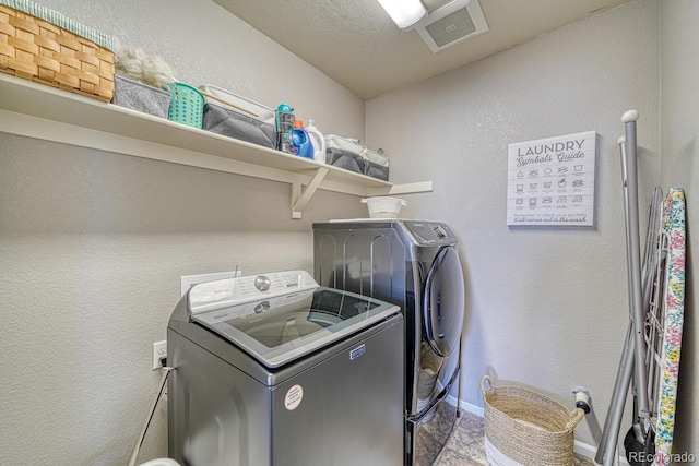 clothes washing area with washing machine and dryer and a textured ceiling