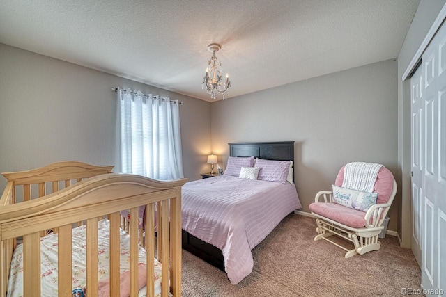 bedroom featuring carpet flooring, a notable chandelier, a textured ceiling, and a closet