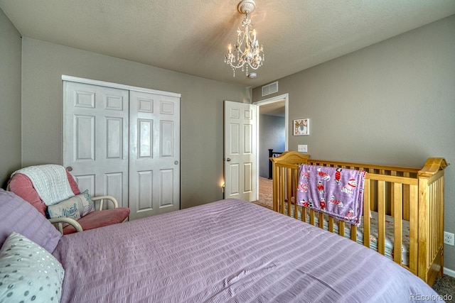 bedroom featuring a notable chandelier, a textured ceiling, and a closet