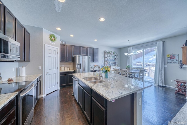 kitchen featuring a textured ceiling, a kitchen island with sink, sink, and appliances with stainless steel finishes