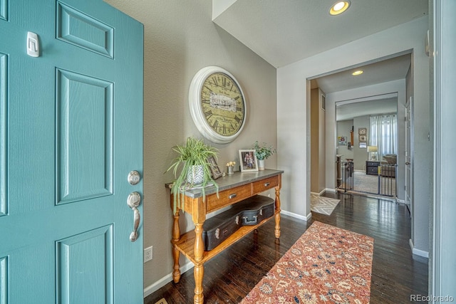 foyer entrance with dark wood-type flooring and vaulted ceiling