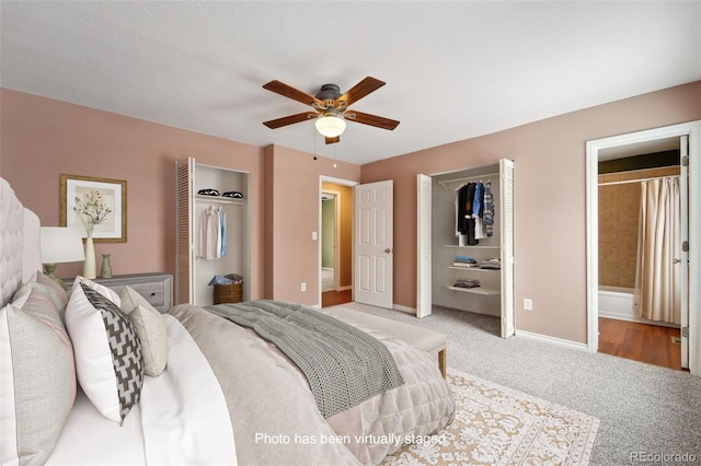 carpeted bedroom featuring multiple closets, connected bathroom, and ceiling fan