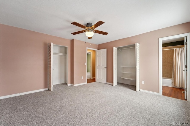 unfurnished bedroom featuring light carpet, two closets, ceiling fan, and ensuite bath