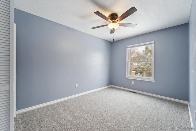 carpeted spare room with a textured ceiling and ceiling fan