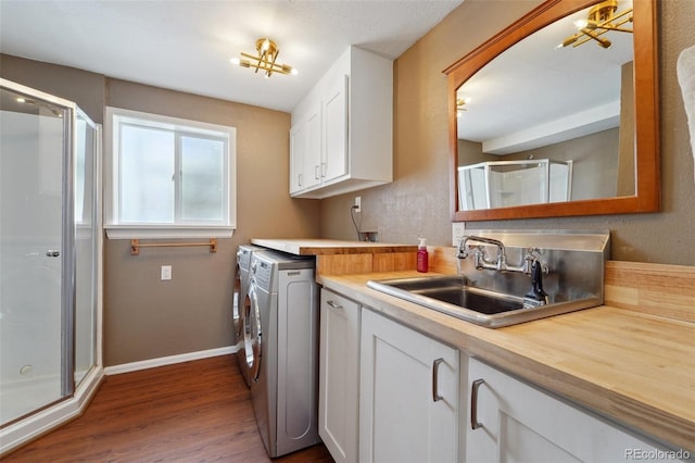 laundry area featuring cabinets, wood-type flooring, separate washer and dryer, and sink