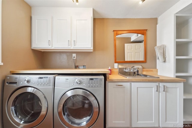 clothes washing area featuring cabinets, washer and clothes dryer, and sink