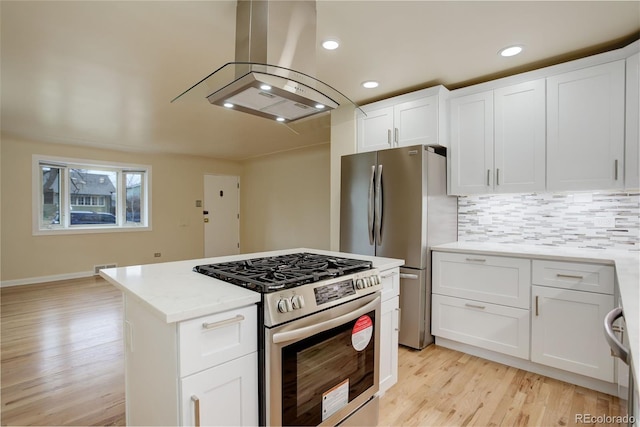 kitchen with light stone countertops, island range hood, stainless steel appliances, and white cabinets