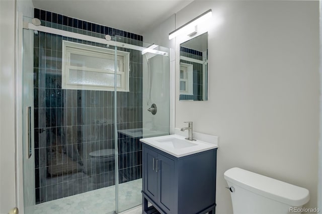 bathroom featuring a shower with door, vanity, and toilet