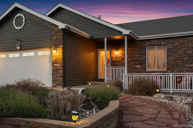 view of front of property featuring covered porch, stone siding, and an attached garage