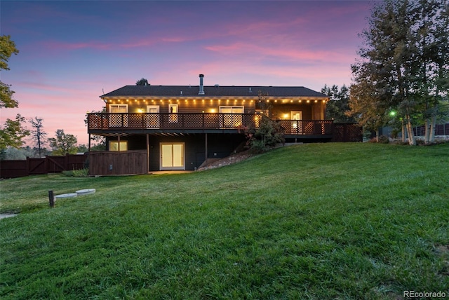 back of house with a deck, a lawn, and fence