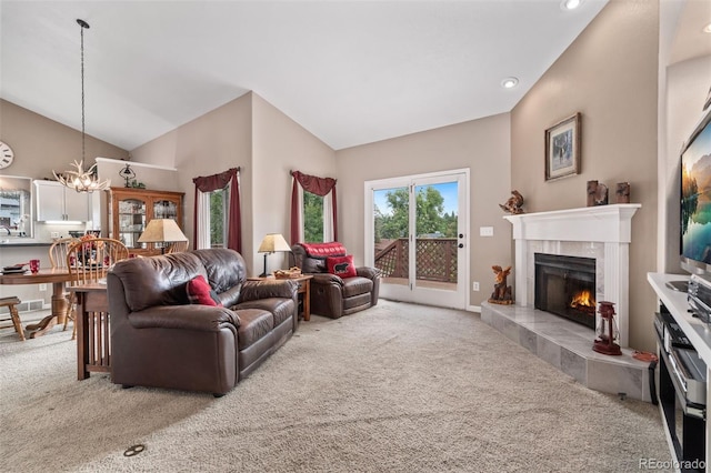 living area with high vaulted ceiling, a tile fireplace, light carpet, visible vents, and an inviting chandelier