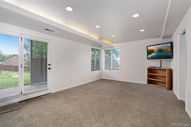 unfurnished living room featuring carpet flooring, plenty of natural light, and baseboards