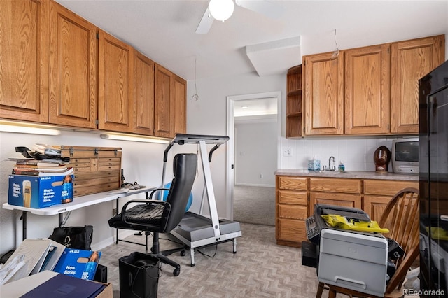 kitchen featuring ceiling fan, light countertops, brown cabinetry, and backsplash