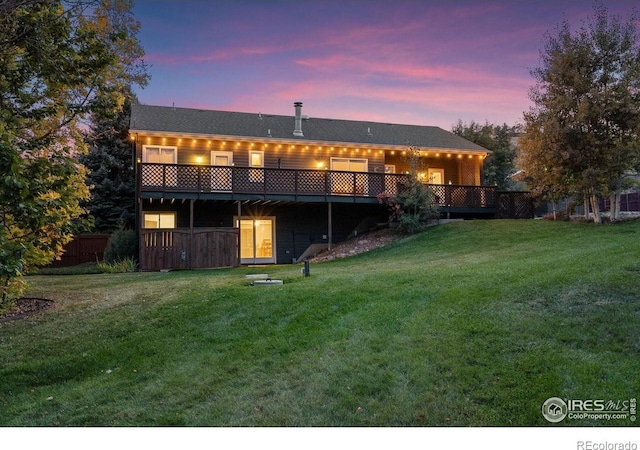 back of property at dusk with a yard and a wooden deck