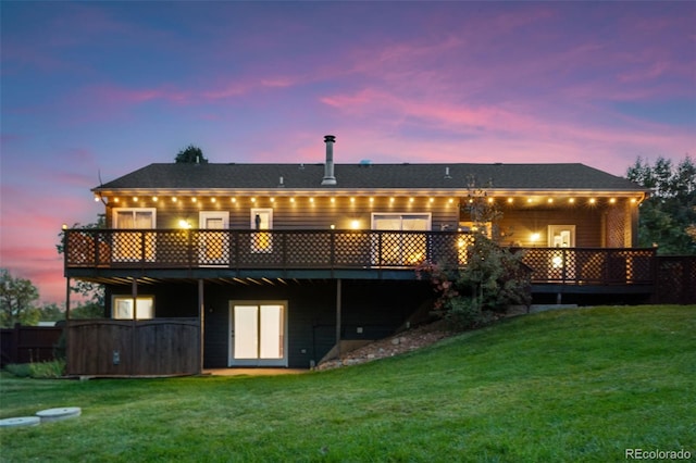 back of property at dusk with a deck and a yard