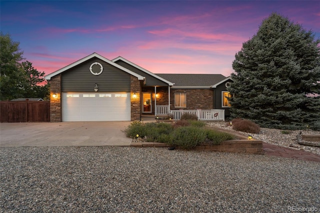 view of front facade featuring stone siding, driveway, an attached garage, and fence