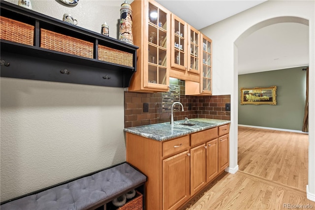 5049 Heatherglen Dr, Highlands Ranch, CO 80130 - kitchen with light wood finished floors, arched walkways, a sink, backsplash, and stone countertops