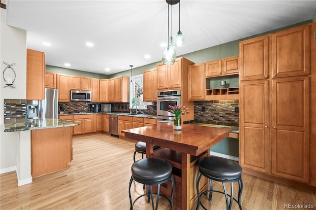 5049 Heatherglen Dr, Highlands Ranch, CO 80130 - kitchen featuring stainless steel appliances, light wood finished floors, pendant lighting, a sink, and decorative backsplash