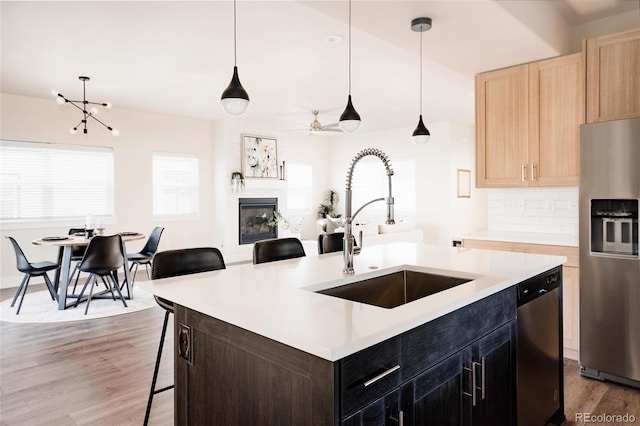 kitchen with pendant lighting, a kitchen breakfast bar, sink, an island with sink, and stainless steel appliances