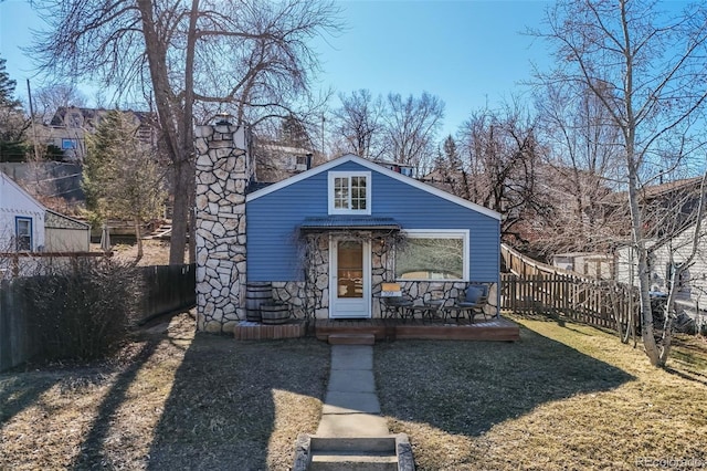 exterior space featuring fence, stone siding, and a chimney