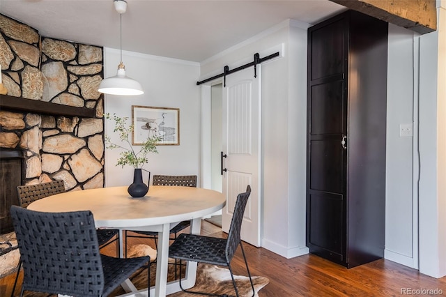 dining area with dark wood-style floors, crown molding, and a barn door