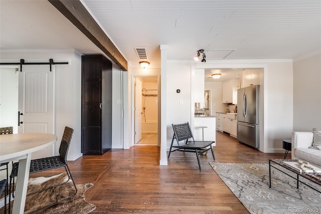 interior space with visible vents, ornamental molding, a barn door, baseboards, and dark wood-style flooring