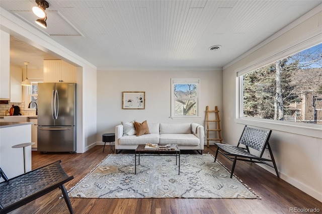 living area with visible vents, crown molding, dark wood-type flooring, and baseboards