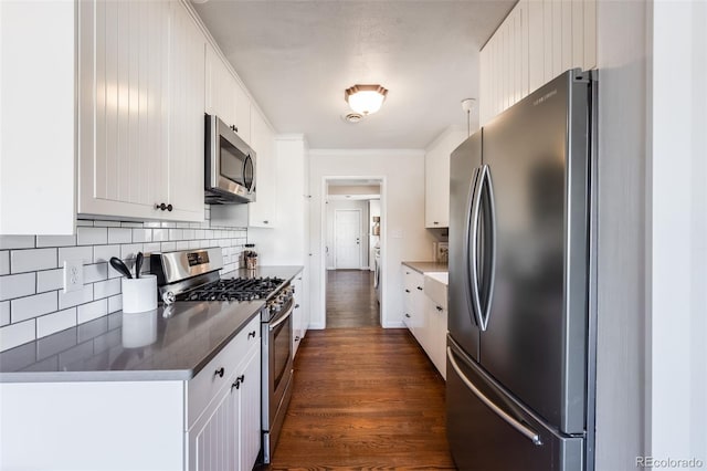 kitchen featuring dark countertops, backsplash, dark wood-style floors, white cabinets, and stainless steel appliances