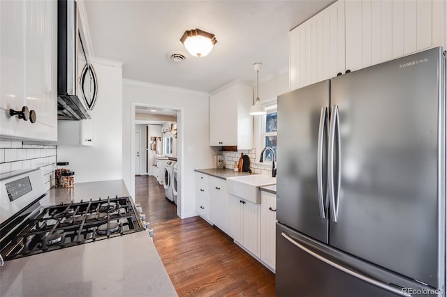 kitchen featuring dark wood-type flooring, a sink, washing machine and dryer, appliances with stainless steel finishes, and white cabinets