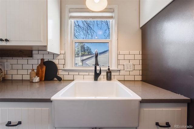 interior details with decorative backsplash, white cabinetry, and a sink