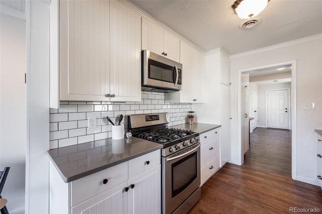 kitchen with dark countertops, visible vents, dark wood finished floors, and appliances with stainless steel finishes