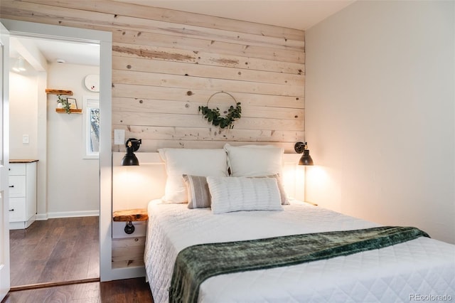 bedroom featuring baseboards, wood walls, and hardwood / wood-style flooring