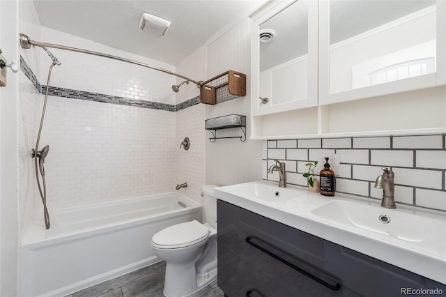 full bathroom with visible vents, backsplash, toilet, and a sink