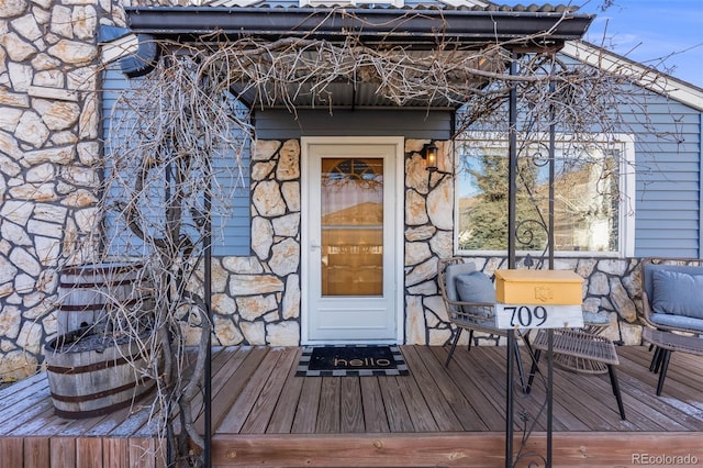 entrance to property featuring stone siding and metal roof