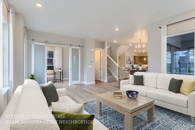 living room featuring a notable chandelier, light hardwood / wood-style flooring, and a barn door