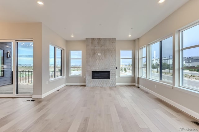 unfurnished living room featuring a tiled fireplace and light hardwood / wood-style floors