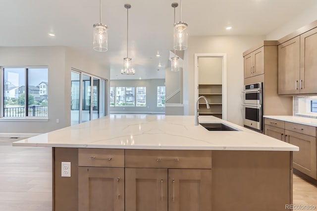 kitchen with light stone countertops, sink, a large island, and stainless steel double oven