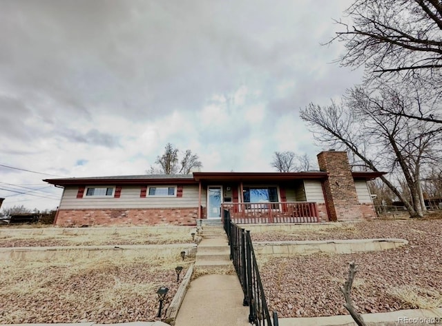 ranch-style home featuring a porch, brick siding, and a chimney