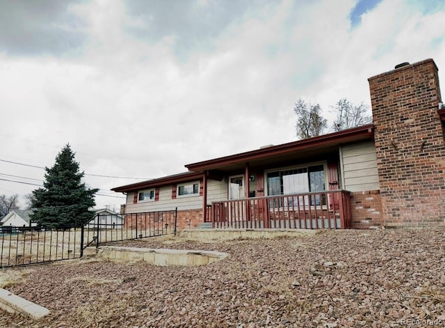 single story home with covered porch, brick siding, a chimney, and fence