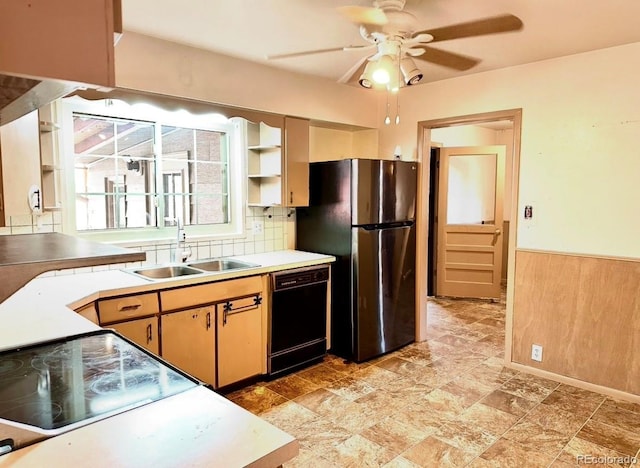 kitchen with black dishwasher, a wainscoted wall, freestanding refrigerator, a sink, and wooden walls